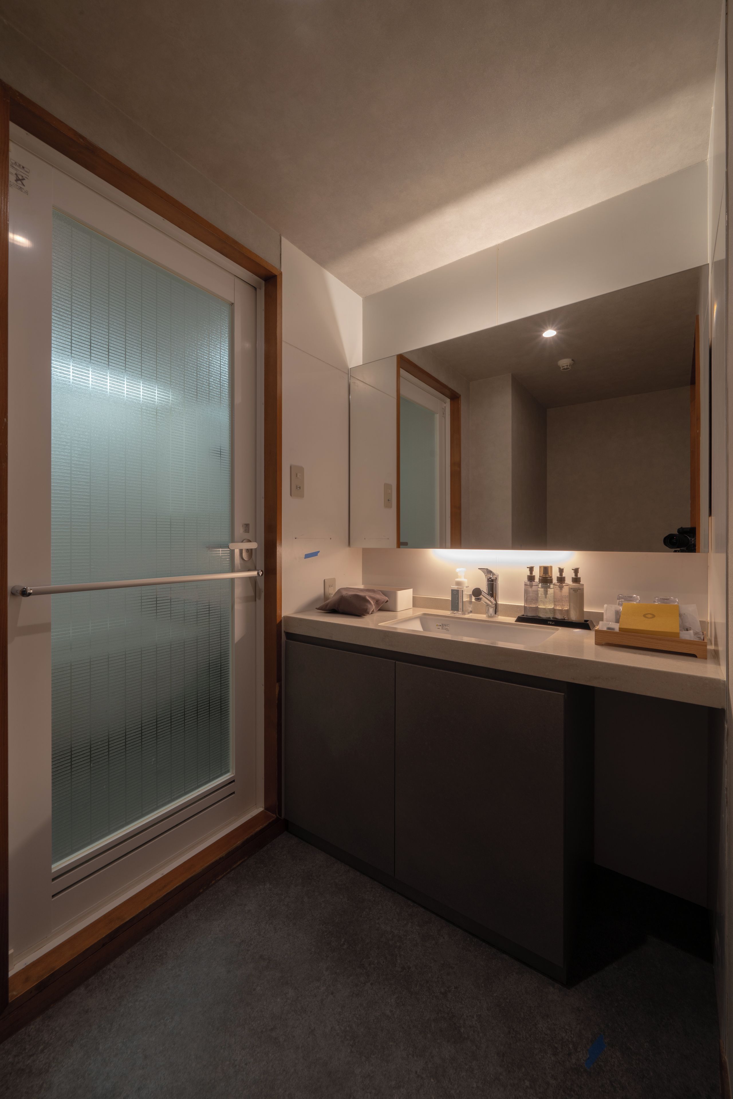 A modern bathroom with a glass shower enclosure, a large mirror, and a countertop with toiletries.