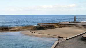 A coastal promenade with a stone pier and a circular viewing platform.