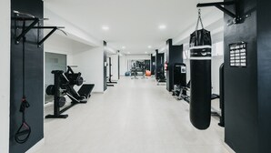 A gym with various exercise equipment, including weight machines and a punching bag.