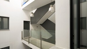 A modern interior with a glass balustrade, a staircase, and pendant lighting. - 1-bedroom in Macarena (Sevilla)
