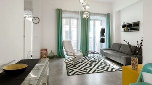 A modern living room with a sofa, a chair, a coffee table, and a floor lamp. - 1-bedroom in Macarena (Sevilla)