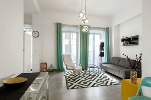 A modern living room with a sofa, a chair, a coffee table, and a floor lamp. - 1-bedroom in Macarena (Sevilla)