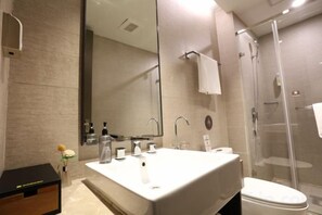 Un baño moderno con un espejo grande, dos lavamanos, un inodoro y una ducha con paredes de vidrio.