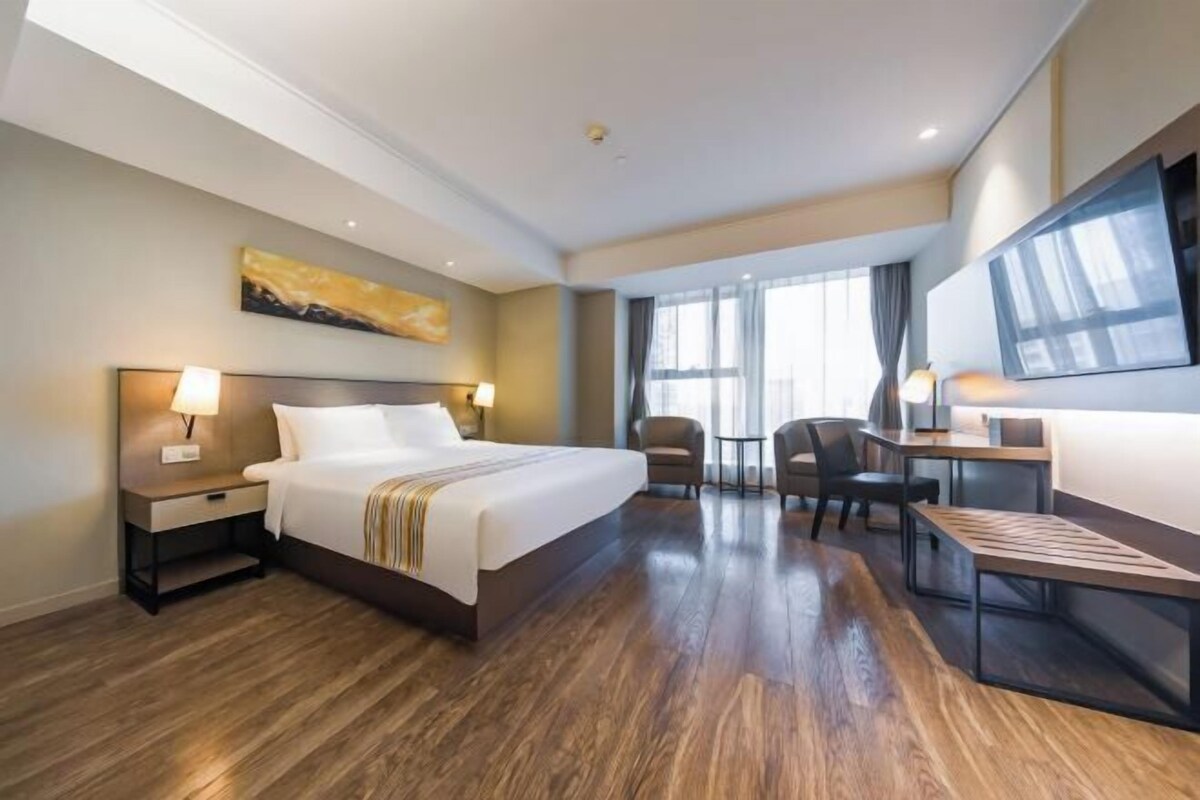 A hotel room with a large bed, bedside tables, a desk, and a chair.