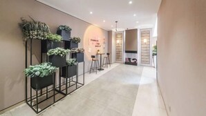 A hallway with a modern design, featuring a series of black metal stands with plants, a small seating area with two chairs and a table, and a wall with a framed sign. - Homeinn Plus Hotel (Xi'an Gaoxin South Second Ring Fengqing Park Subway Station) (Xi'an)