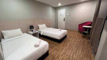 Une chambre d’hôtel avec deux lits, une petite table avec une lampe, une chaise et une porte.