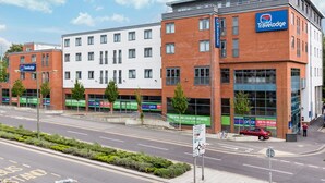 A Travelodge hotel with a modern brick facade, large windows, and a visible sign for a new retail and leisure opportunity. - Travelodge Camberley Central (Camberley)