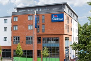 Un hotel Travelodge con fachada de ladrillo, ventanas amplias y un cartel.