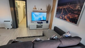 Una sala de estar moderna con una televisión de pantalla plana, un sofá, una mesa de centro y vistas a la ciudad.