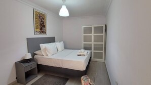 Un dormitorio pequeño y ordenado con cama, mesita de noche y ventana con paneles de vidrio esmerilado.