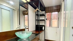 A modern bathroom with a glass bowl sink, a mirror, and a built-in shelf unit. - Hub53 Coworking & Coliving Space (Chiang Mai)