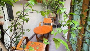 An outdoor seating area with wooden tables and chairs, surrounded by greenery and potted plants. - Hub53 Coworking & Coliving Space (Chiang Mai)