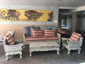 A cozy living area with a sofa and two armchairs, a coffee table, and a large wall painting. - Hub53 Coworking & Coliving Space (Chiang Mai)