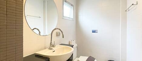 A modern bathroom with a white sink, mirror, and toilet.