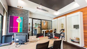 A modern office space with multiple workstations, a large wall-mounted sign, and a bookshelf with decorative items. - Hub53 Coworking & Coliving Space (Chiang Mai)