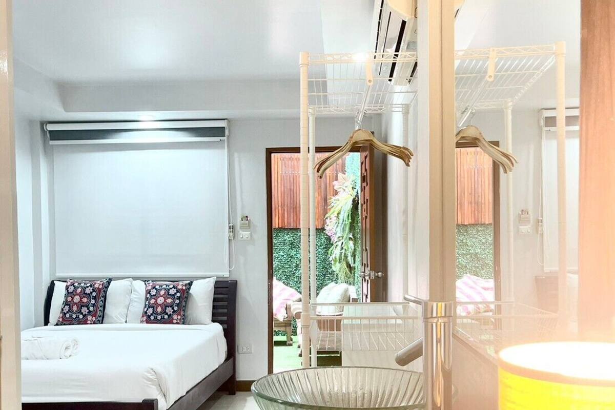 A modern bedroom with a bed, a hanging chair, and a large mirror.