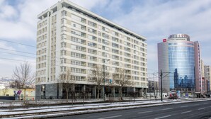 Un hôtel à plusieurs étages, doté d’une façade moderne, situé à côté d’un bâtiment en verre orné d’une enseigne.