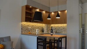 Une cuisine moderne avec des meubles en bois, un dosseret carrelé et des luminaires suspendus. On y trouve également un coin repas avec une table et des chaises.