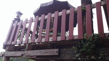 A wooden balcony with a railing, a small table, and a potted plant.