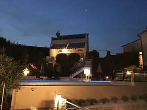 A two-story building with a balcony, a staircase, and a swimming pool.
