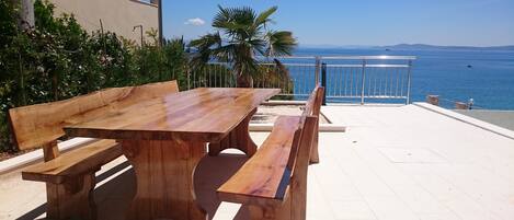 Una mesa de madera y bancos en un patio con vistas al mar.