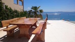 A wooden table and benches on a patio with a view of the sea.