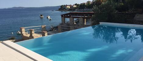 Ude pool med udsigt til havet og både.