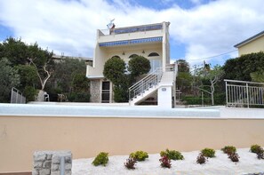 A modern two-story building with a balcony, a staircase, and a stone wall in the foreground. - Beautiful villa with amazing swimming-pool, seafront (Okrug Gornji)