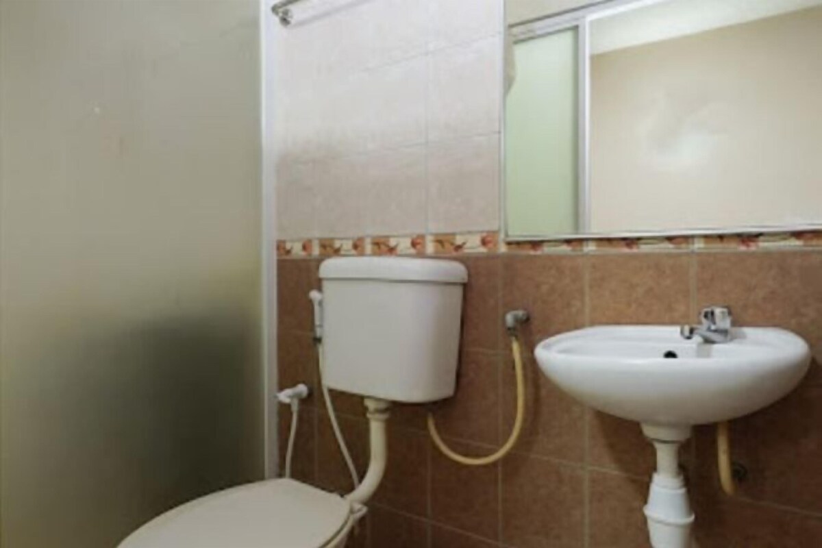 A bathroom with a toilet, sink, and a mirror.