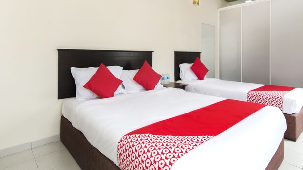 A hotel room with two beds, each with white bedding and red accents, a large mirror, and a wardrobe. - Hotel O 91 @ Bukit Mewah (Kajang)