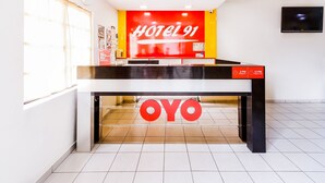 A hotel reception desk with a red and yellow sign reading "HOTEL 91" and a digital clock displaying "2 PM Check-in" and "12 PM Check-out". - Hotel O 91 @ Bukit Mewah (Kajang)
