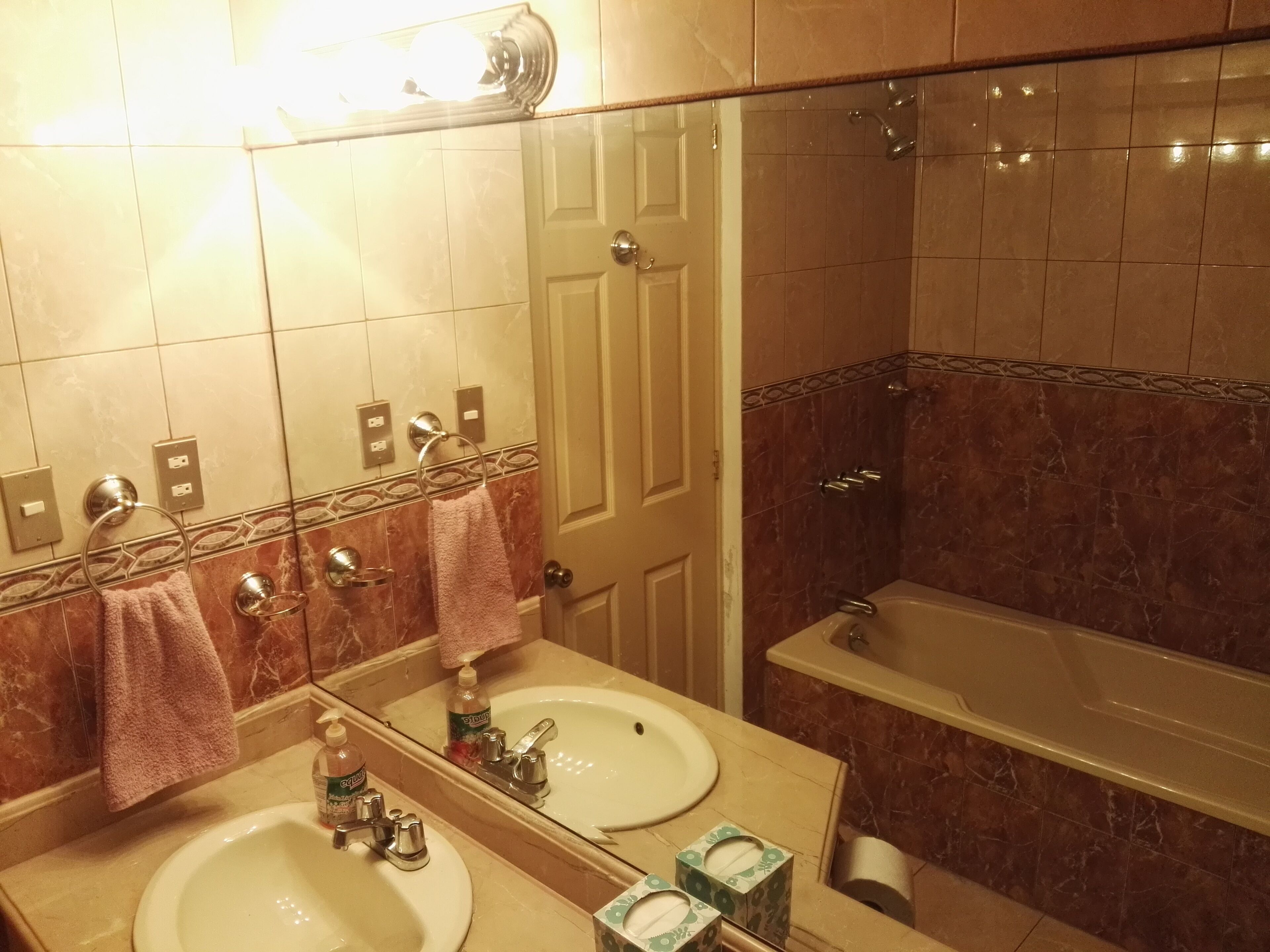 A bathroom with two sinks, a mirror, a towel rack, a shower, and a toilet.