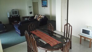 Un salon comprenant une table à manger, des chaises, un canapé, un téléviseur et un four à micro-ondes.