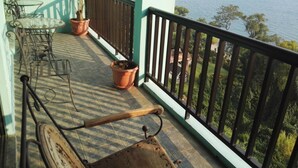 Un balcon avec vue sur la mer, une table avec des chaises et des plantes en pot.
