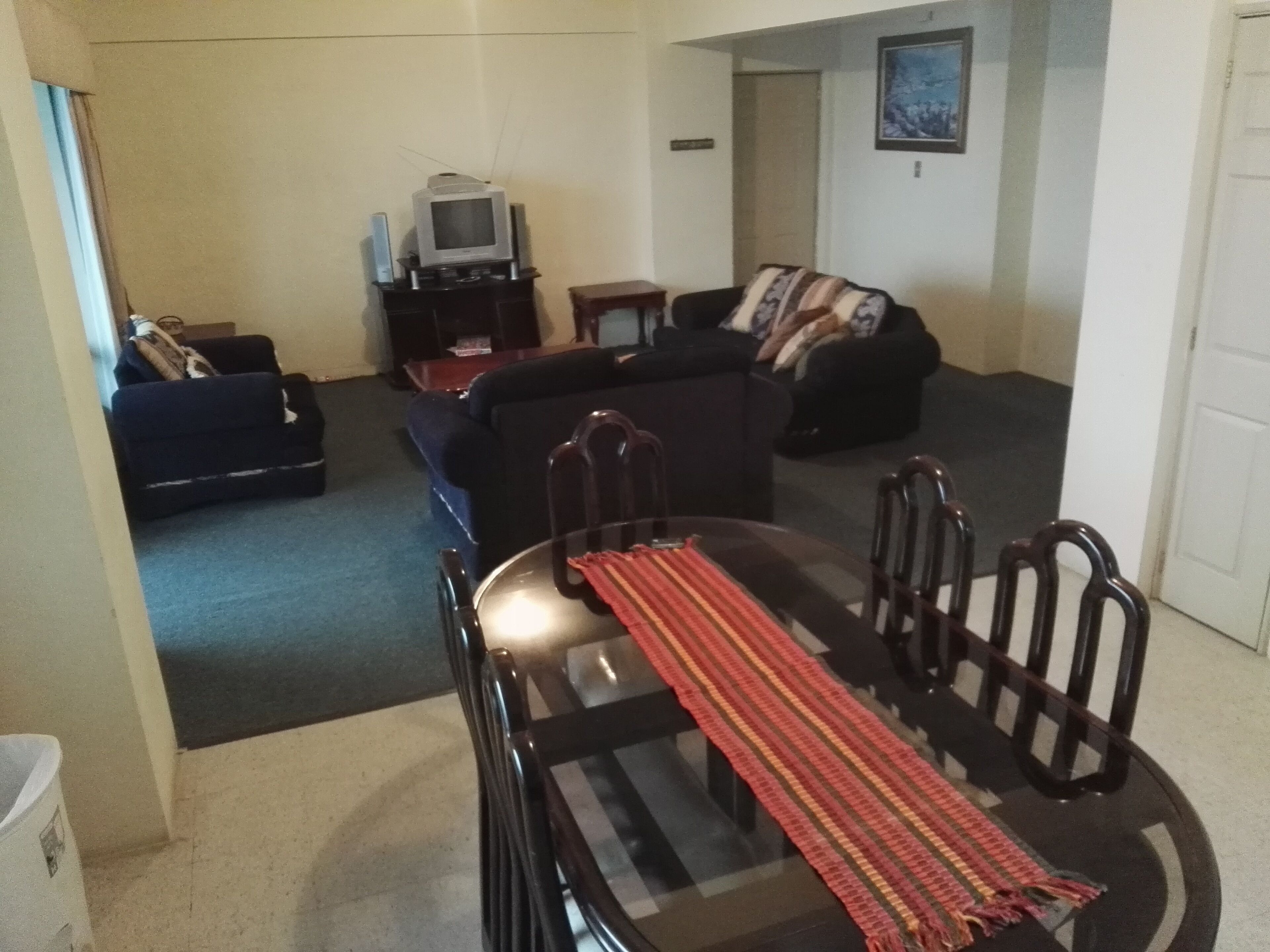 Una sala de estar con una mesa de comedor, sillas, sofás y un televisor.