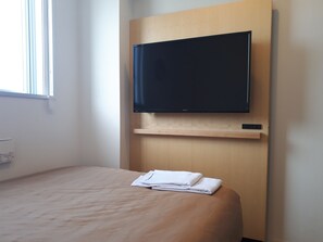 A hotel room with a bed, a flat-screen TV mounted on a wooden panel, and a window with blinds. - Center Hotel Narita 2 R51 (Narita)
