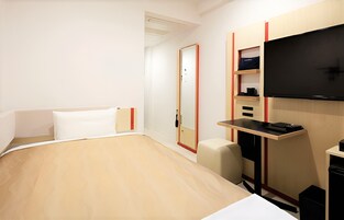 Habitación de hotel con cama, escritorio, silla, televisor y armario.