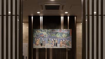 A corridor with a tiled floor, a large wall-mounted artwork depicting a traditional scene, and vertical wooden slats on either side.
