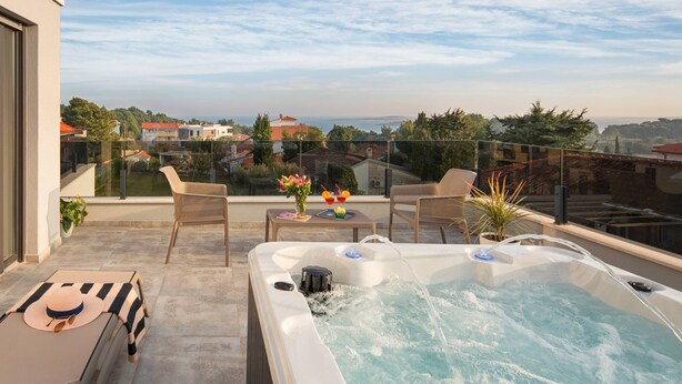 Een terras op het dak met een jacuzzi, zitplaatsen buiten en uitzicht op de stad.