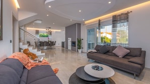 Een moderne woonkamer met een bank, een salontafel en een trap die leidt naar een eetruimte.