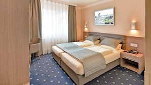 Ein Hotelzimmer mit einem großen Bett, einem Schreibtisch, einem Stuhl und einem fenster mit Vorhängen.