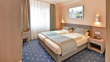 Camera d'albergo con un letto grande, una scrivania, una sedia e una finestra con tende.