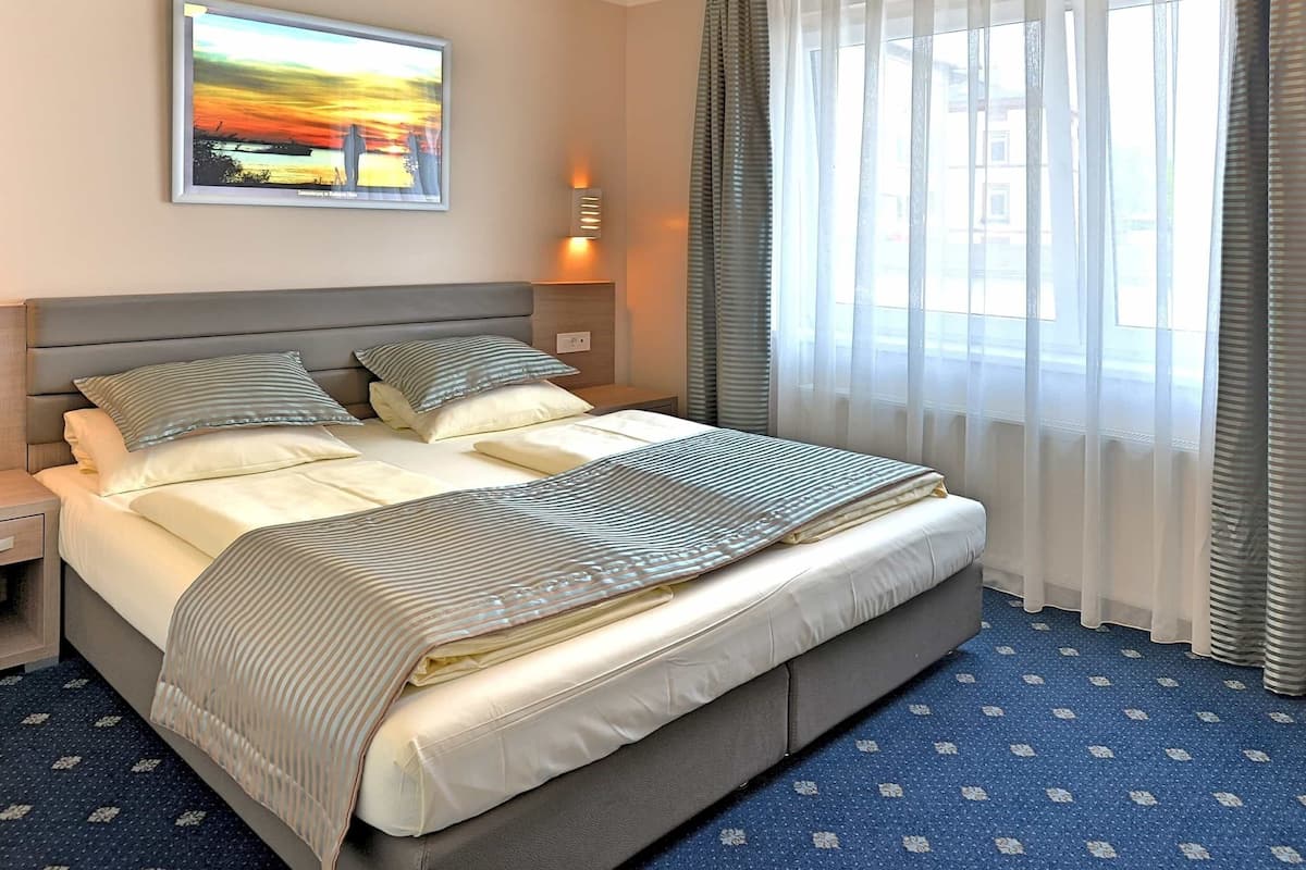 Ein Hotelzimmer mit einem großen Bett, einem Nachttisch, einer Wandlampe und einem Gemälde über dem Bett.