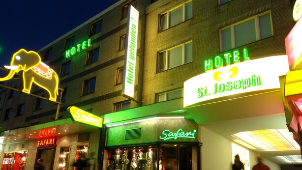Ein Hotel mit Neonreklame, darunter 'Hotel St. Joseph' und 'Safari'.
