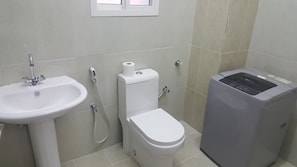 A bathroom with a sink, toilet, and a trash bin. - Today House Suites (Salalah)