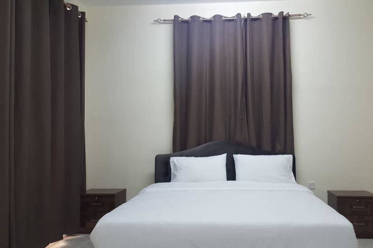 A bedroom with a bed, two bedside tables, and a curtain.