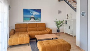 A living room with a sofa, ottoman, and a painting of a beach scene. - Cozy home in Galizana (Galizana)