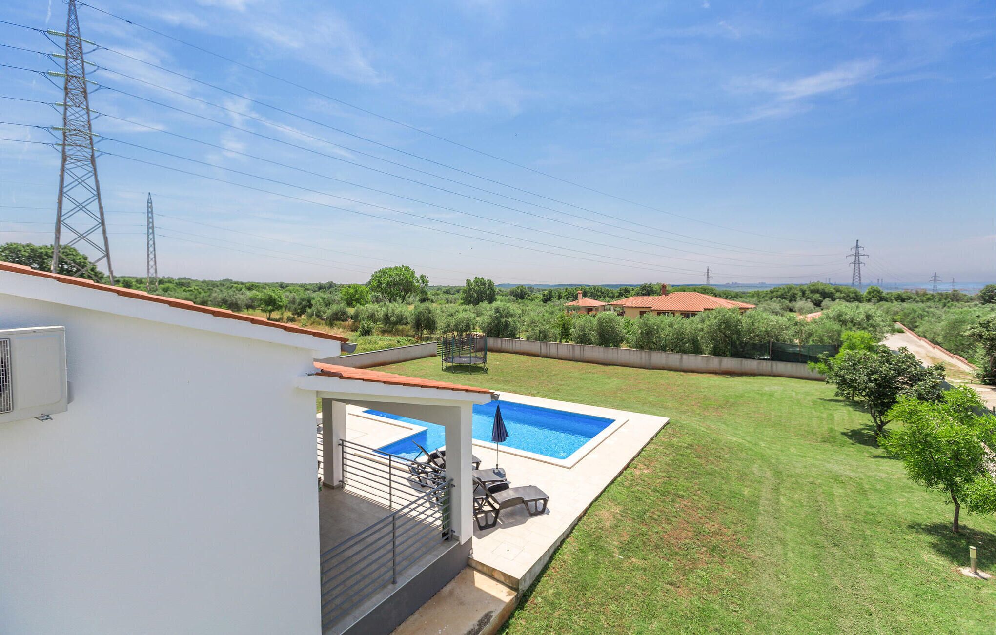 A residential property with a swimming pool, a covered patio, and a view of the surrounding landscape.