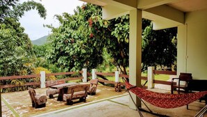 An outdoor patio with wooden furniture, a hammock, and a view of lush greenery and hills. - Pai Backpackers Paradise - Adults Only (Pai)