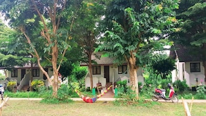 A house with a porch, surrounded by trees and a hammock. - Pai Backpackers Paradise - Adults Only (Pai)